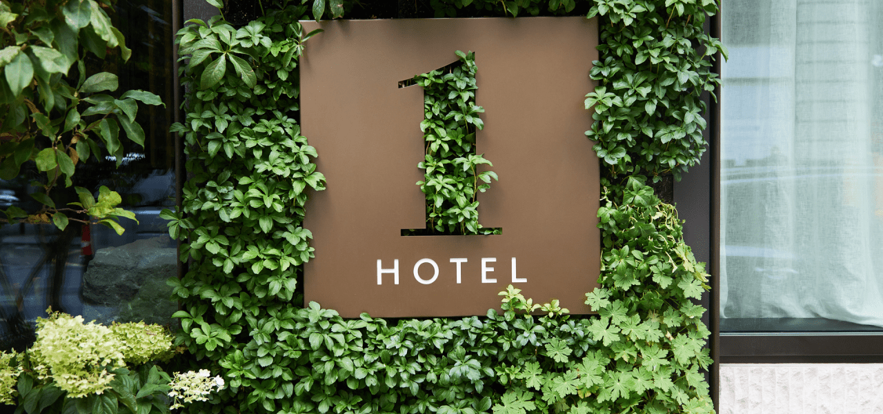 A 1 Hotel sign surrounded by a leafy green wall